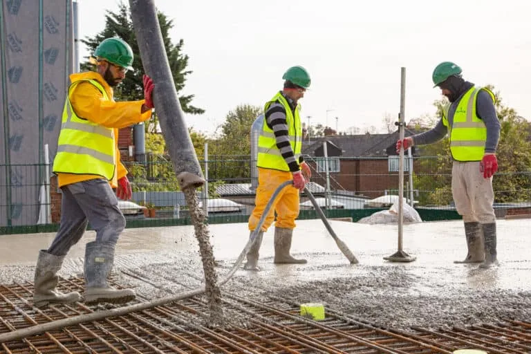 Construction workers pouring concrete on building site.