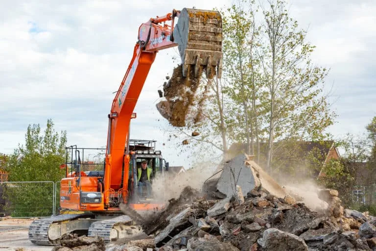 Excavator demolishing rubble at construction site.