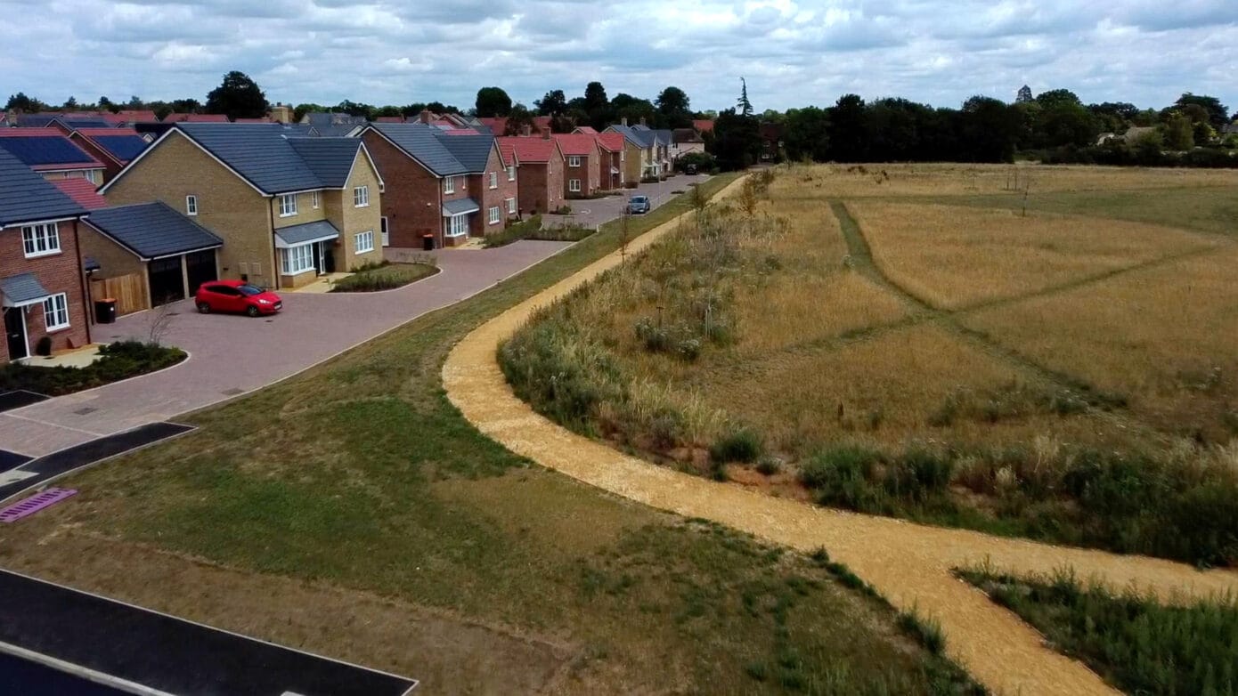 Suburban houses by grassy path and field